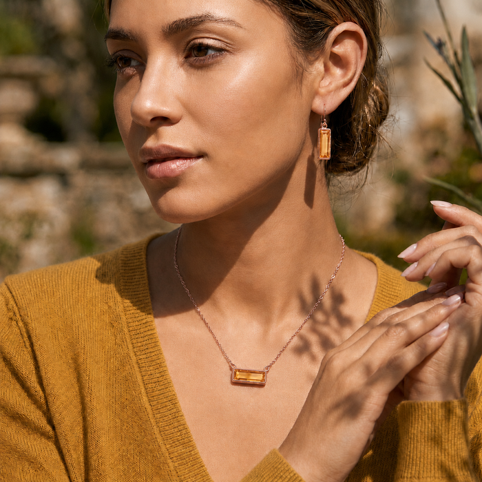 Woman wearing matching Citrine Quartz earrings and necklace with a mustard blouse