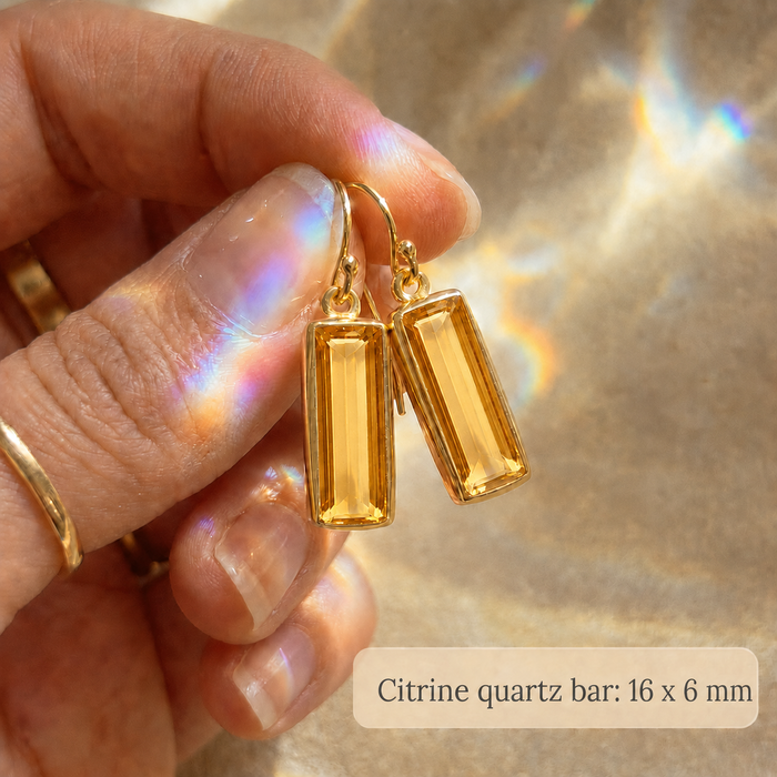 Citrine Quartz rectangular earrings held in a hand for size reference