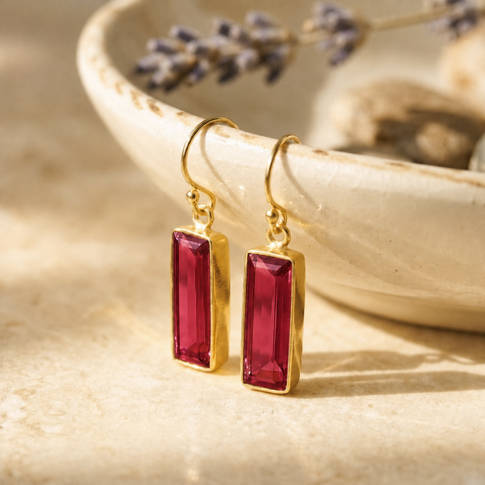 Ruby Quartz baguette drop earrings in yellow gold vermeil on a cream jewelry dish