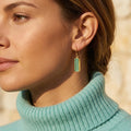 Model wearing aqua chalcedony rectangular gemstone earrings with a gold hook ear wire.