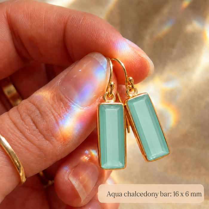 Close-up of 16 x 6 mm aqua chalcedony baguette gemstone bars held in hand.