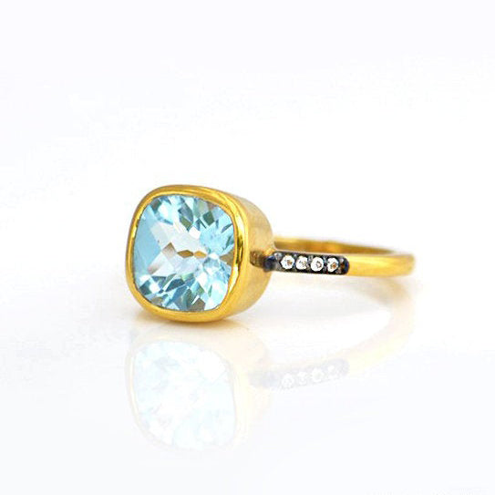 Gold plated blue topaz with white topaz pave setting ring on white background. December gemstone, december birthstone, december birthday. Bezel setting.