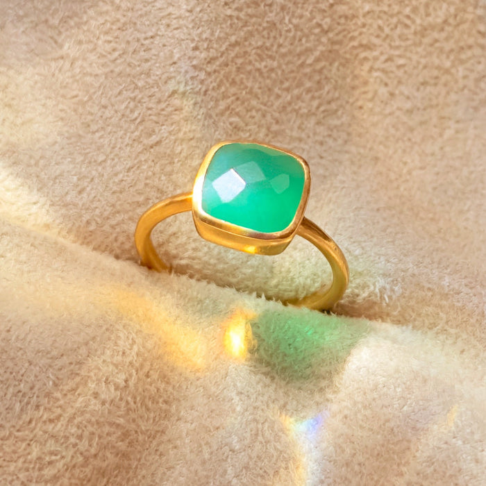 Green onyx cushion cut bezel set ring photographed on soft neutral fabric, featuring a faceted square cushion green onyx gemstone framed in a smooth gold bezel setting. Minimalist May birthstone ring designed for everyday wear, stacking, or elegant gifting. Handmade gemstone ring available in sterling silver or gold vermeil, showcasing a timeless design with a vibrant green stone and delicate band, perfect as a meaningful birthstone or anniversary gift.