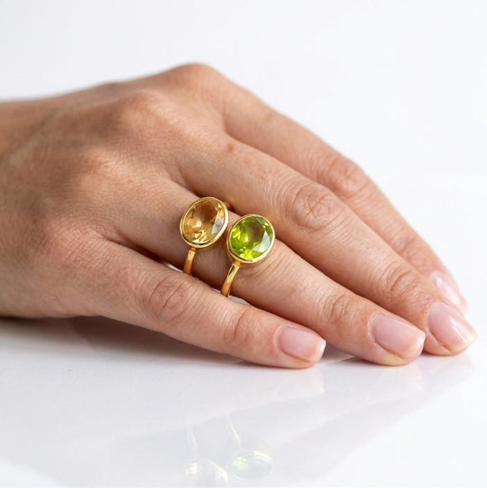 Model wearing citrine and peridot birthstone ring on hand against white background