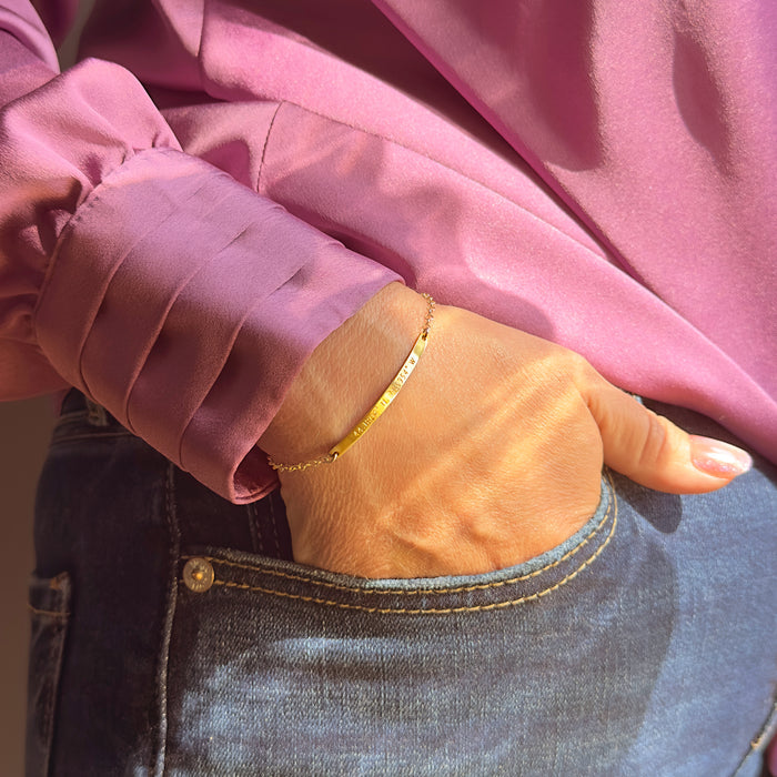 Casual lifestyle image of engraved skinny bar bracelet styled with everyday outfit, personalized coordinates bracelet worn on wrist, minimalist dainty bar bracelet in gold filled finish, modern personalized jewelry for women, latitude longitude bracelet for meaningful location, handcrafted bar bracelet perfect for daily wear and gifting
