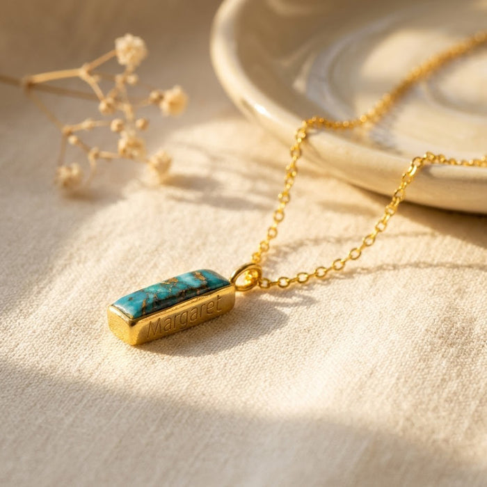 Personalized turquoise bar necklace with engraved name on a gold chain, styled as a December birthstone gift.