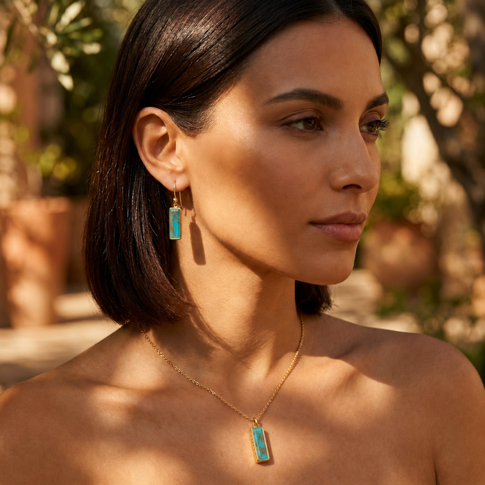 Copper turquoise vertical bar necklace worn by a model with matching earrings in natural outdoor light.