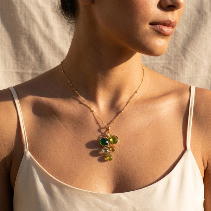 Woman wearing personalized birthstone necklace with round gemstone charms, styled as a meaningful gift for Mom or Grandma.