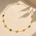 Custom birthstone station necklace with green and yellow natural gemstones spaced along a delicate yellow gold chain