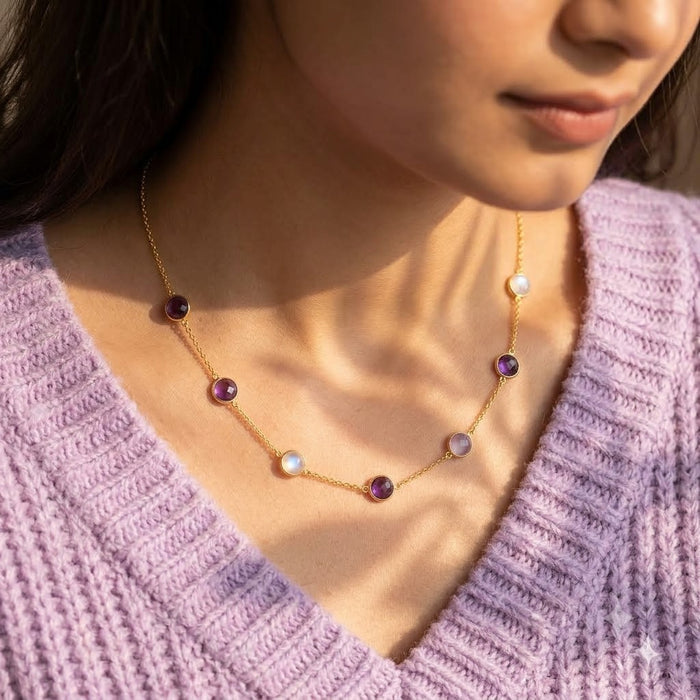 Woman wearing a custom family birthstone necklace with purple, pink and white gemstones in a delicate station design