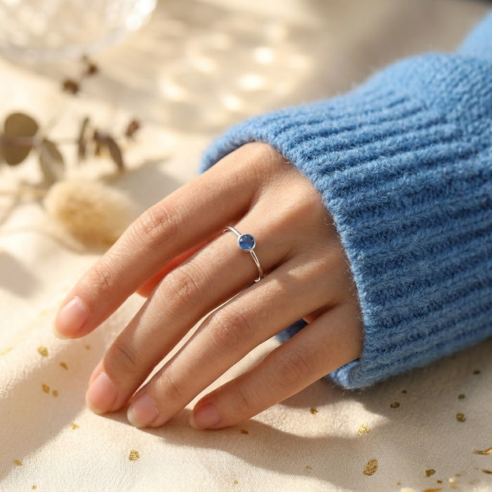 Hand modeling delicate kyanite ring in gold, dainty September birthstone ring with sapphire blue gemstone