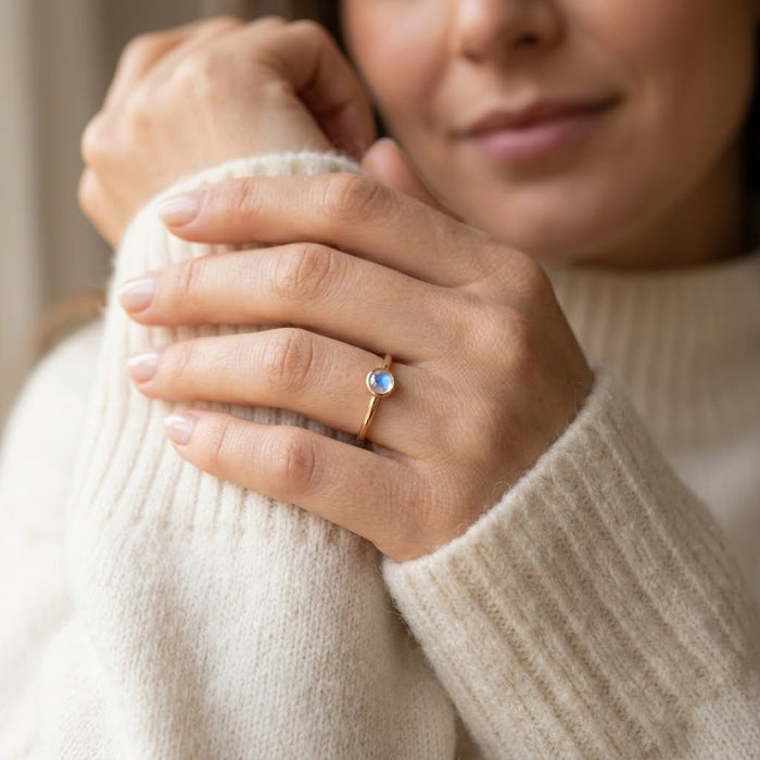 Woman wearing moonstone ring, minimalist June birthstone stacking ring with iridescent gemstone