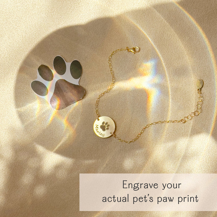 Gold bracelet engraved with an actual paw print from a pet photo, custom pet memorial jewelry with engraved name and adjustable fit option.