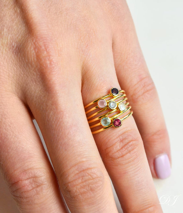 Model is stylishly stacking rings. Stackable! Ring combo with six gold plated rings stacking ring set tiny round birthstones black onyx, pink chalcedony, blue topaz, moonstone, aqua chalcedony and ruby.gemstone ring. November birthstone.