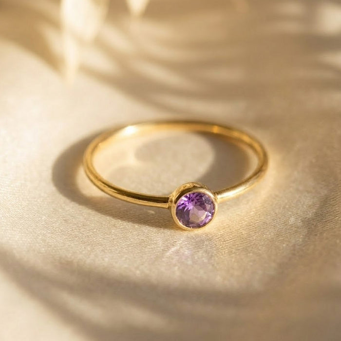 Amethyst bezel set ring on neutral background, dainty purple gemstone gold ring