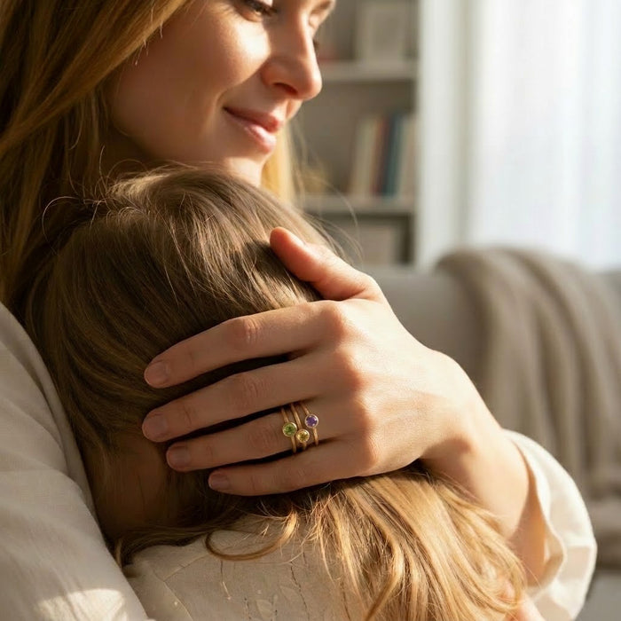 Mother hugging child while wearing a stackable birthstone ring set, meaningful family jewelry gift for mom, grandma, or new mother