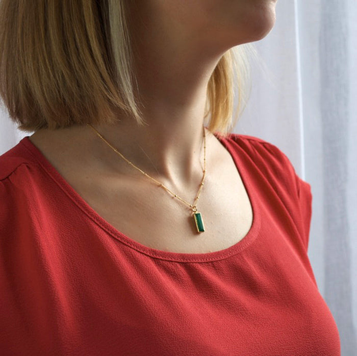 Model in red top is wearing a gold filled satellite chain with the green tourmaline birthstone may birthstone