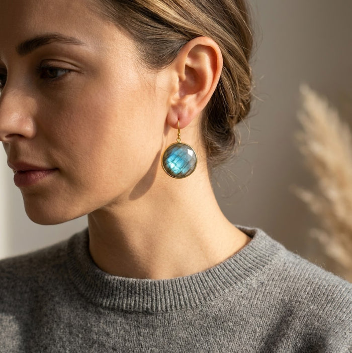 Model wearing small labradorite earrings in soft natural light, featuring dainty blue-green gemstone drops in gold for a minimalist everyday jewelry look.
