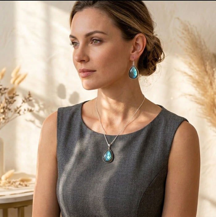 Model wearing matching labradorite necklace and earrings, featuring blue-green gemstone drops in gold settings for a coordinated jewelry set.