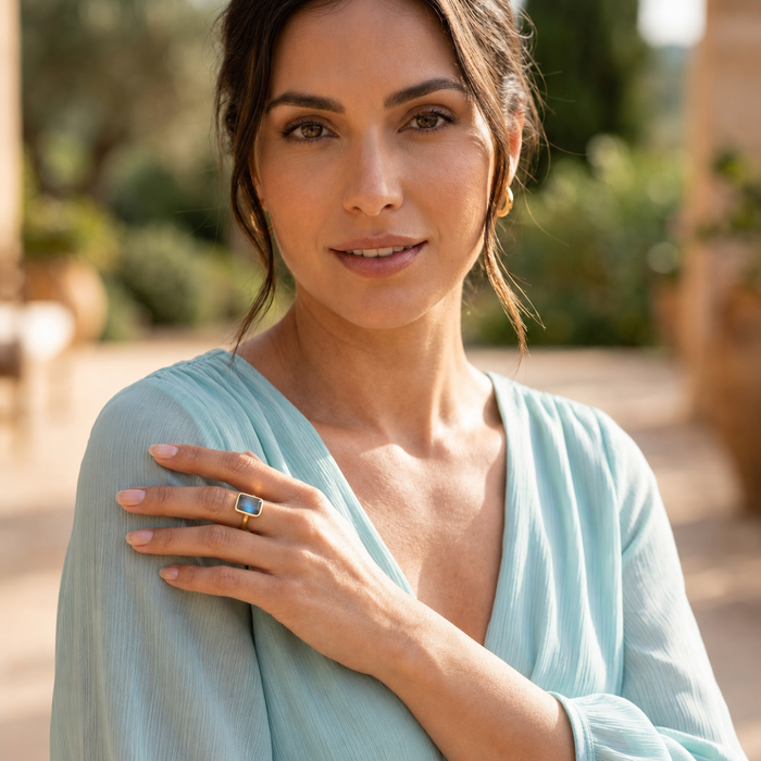 Model wearing blue flash labradorite ring with pastel aqua colored blouse.