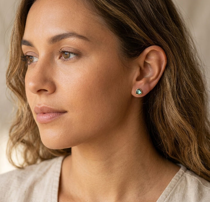 Model wearing labradorite triangle stud earrings in yellow gold finish, a minimalist gemstone jewelry gift for everyday wear.