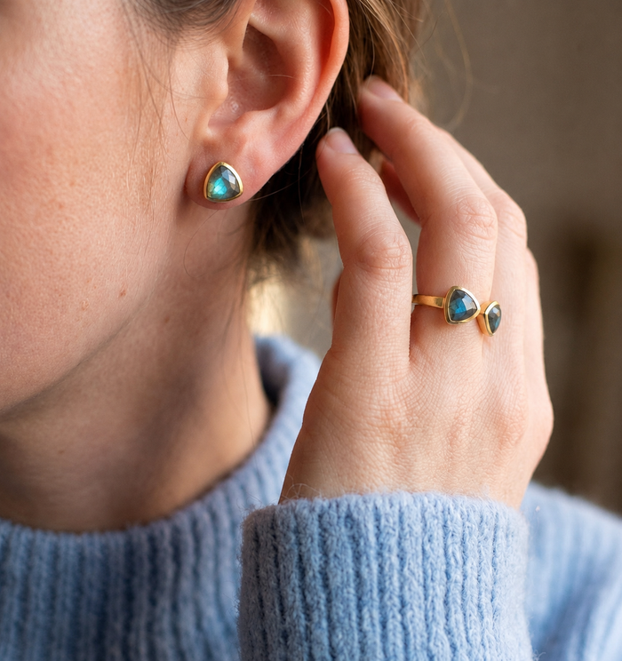Model wearing labradorite triangle stud earrings with matching ring, showing coordinated gemstone jewelry set.
