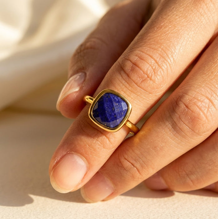 Woman wearing lapis lazuli bezel ring in gold, bold cushion cut gemstone ring styled as modern statement jewelry