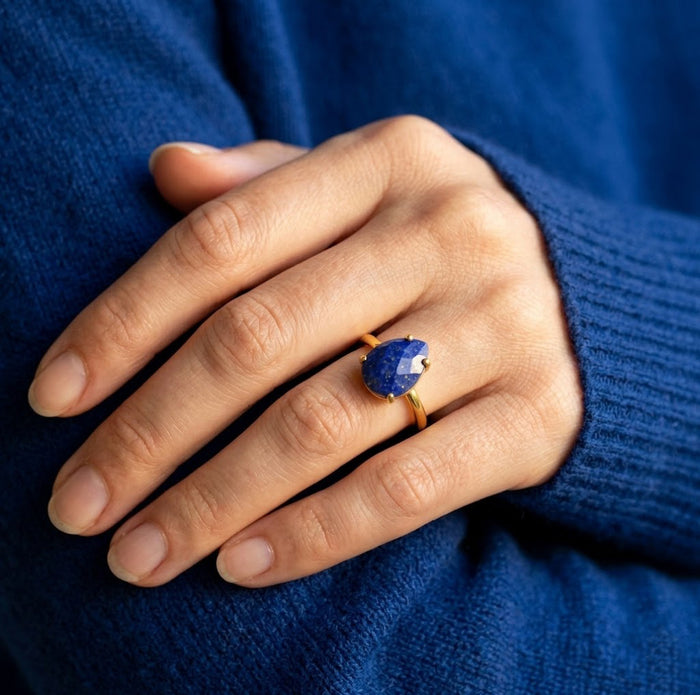 Model wearing a lapis lazuli teardrop ring with a blue sweater, styled as a September birthstone ring for everyday wear.
