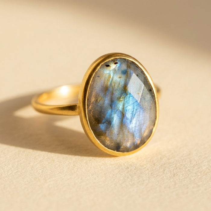 Oval labradorite ring in 18K yellow gold vermeil, natural gemstone ring with blue flash on a soft neutral background.