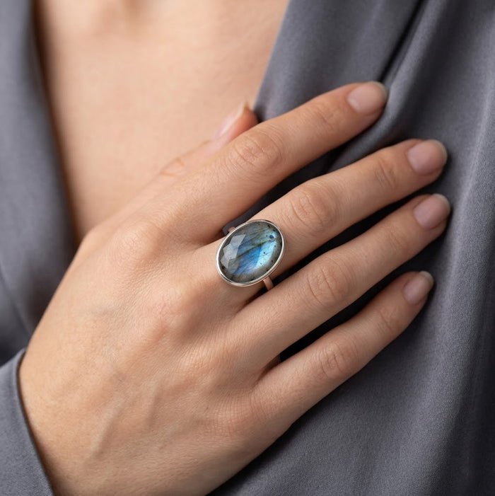 Model wearing oval labradorite gemstone ring, a statement ring with blue-green flash in gold vermeil or sterling silver.