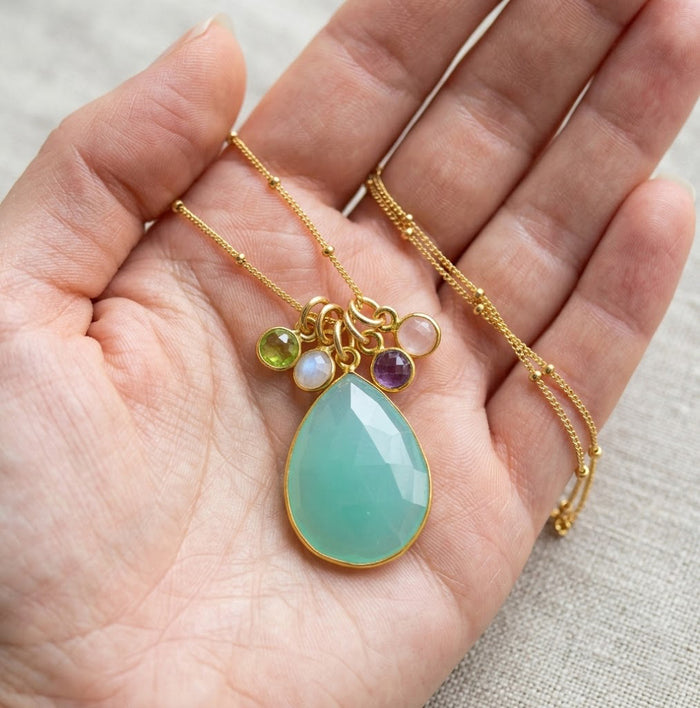 Mom birthstone necklace held in palm with 18 by 25 mm teardrop and 6 mm stones