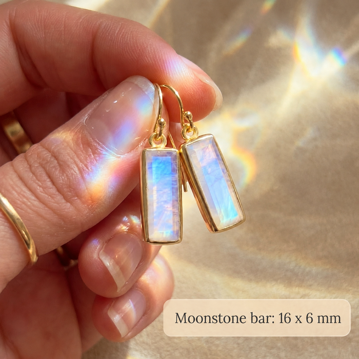 Close-up of moonstone bar earrings held between fingers with text noting the 16mm x 6mm moonstone bar size.