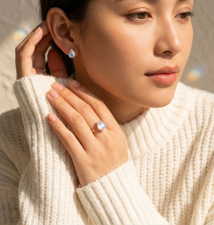 Model wearing moonstone ring and matching moonstone earrings with cream sweater