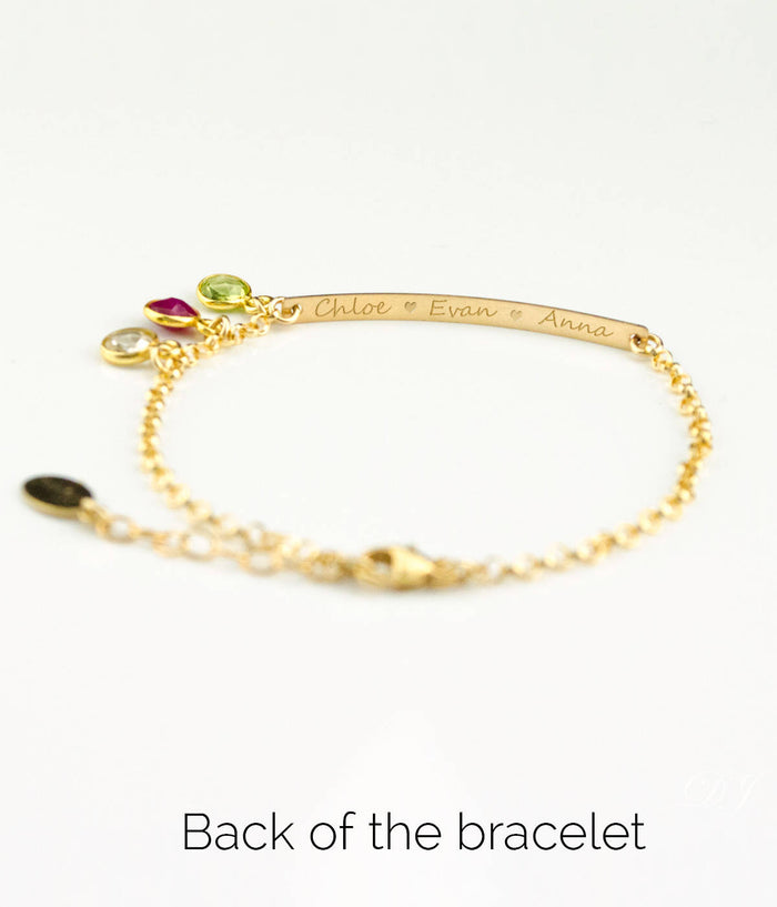 Back of gold filled bracelet has been engraved with names in script font. Peridot, ruby and clear birthstones are shown.