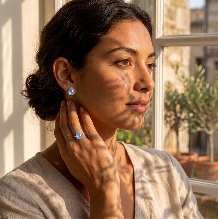 Model wearing natural moonstone stud earrings with soft blue flash, a delicate everyday gemstone earring style for women.