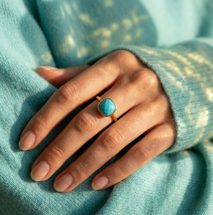 Model wearing a natural turquoise cushion ring with an aqua sweater.