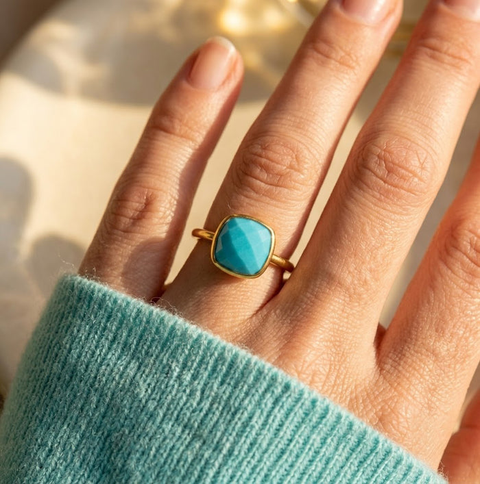 Turquoise cushion bezel ring worn on hand in soft natural light.