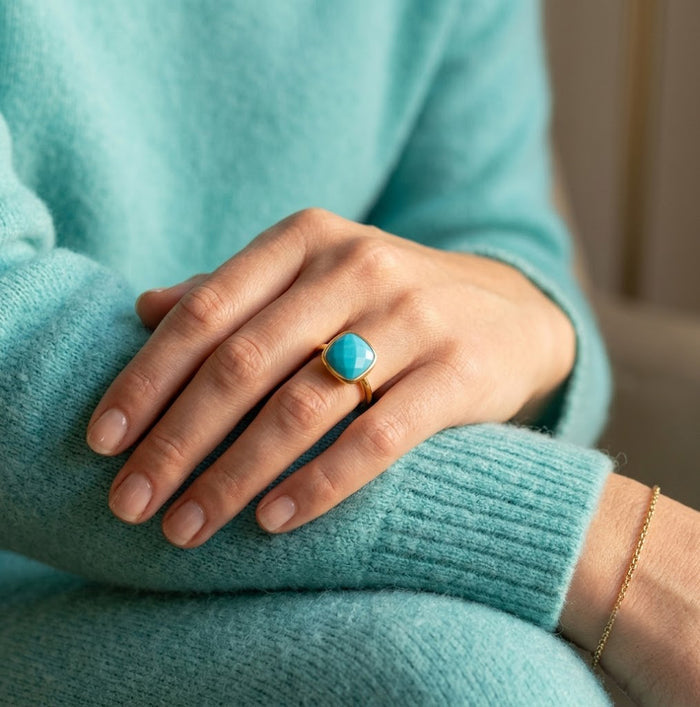 Turquoise cushion ring worn with cozy aqua sleeve for everyday styling.