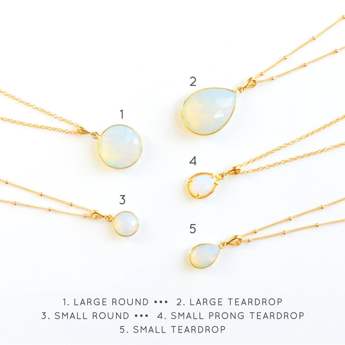 Collection of opalite birthstone necklaces with round and teardrop pendants on display cards. October birthstone jewelry handmade in Massachusetts — a thoughtful jewelry gift for her, bridesmaid, or mom. Dainty opal necklace in gold, silver, and rose gold finishes.