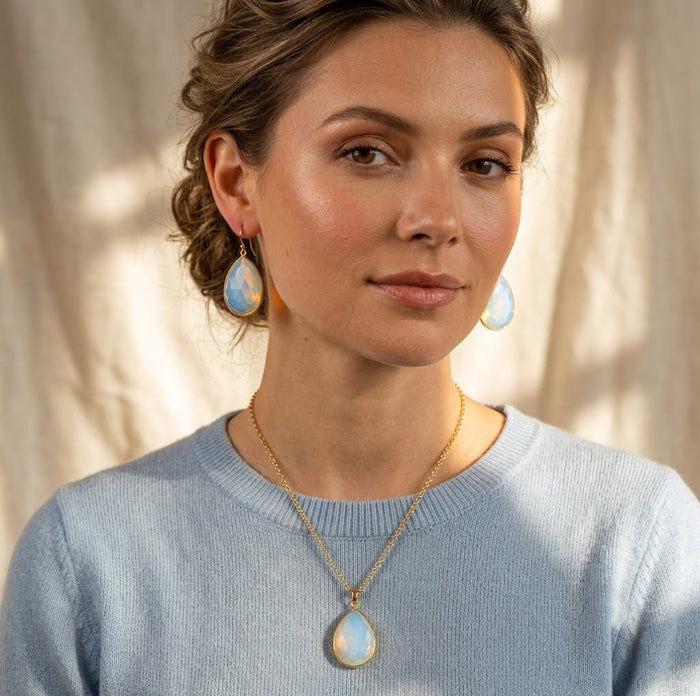 Model wearing an opalite teardrop necklace and matching earrings in a soft blue sweater.