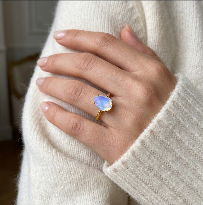 Model wearing an opalite teardrop birthstone ring, a dainty October gemstone ring for women in a delicate prong setting.
