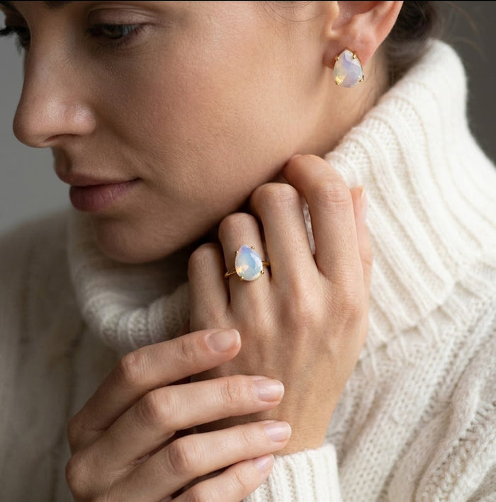 Woman wearing an opalite teardrop ring with matching birthstone earrings, a soft October birthstone jewelry gift for her.