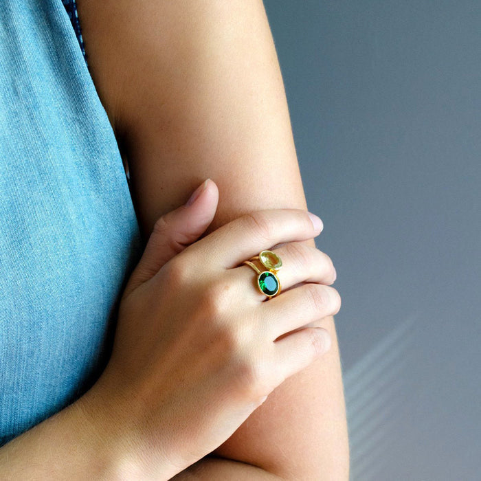 Dainty bezel set emerald ring worn stacked with minimalist bands, showcasing the oval green quartz sparkle in natural light. Lightweight, nickel-free gold vermeil ring designed for daily wear; available as a sterling silver emerald ring for cool-tone outfits. Ideal gift for her, promise ring, graduation jewelry, or anniversary present; handcrafted, sizes 5–10.