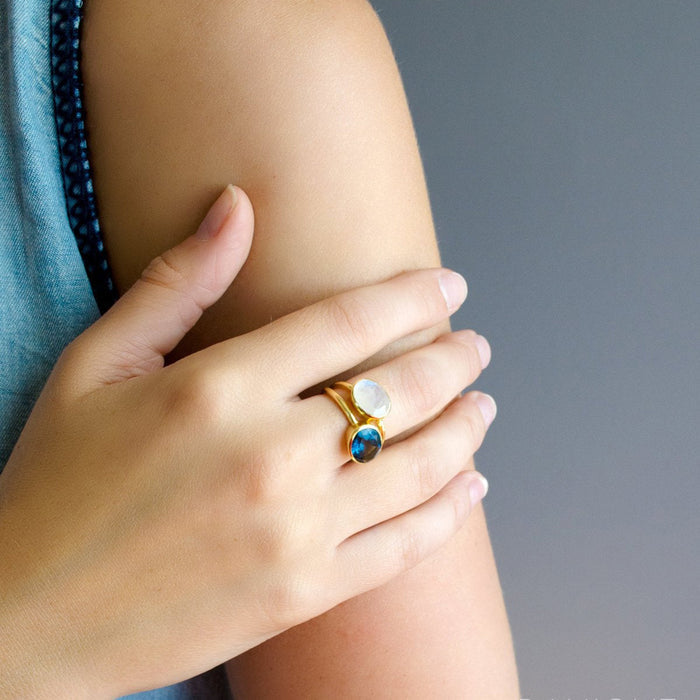 Dainty kyanite oval ring worn on hand for scale; slim stackable band and bezel-set sapphire-blue gemstone create a minimalist, everyday look; perfect September birthstone gift for her, bridesmaids, or anniversary; pairs with other stacking rings in silver or gold.