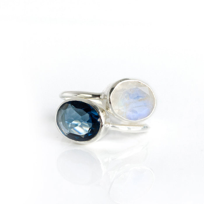 Example stacking rings set pairing a sapphire-blue kyanite oval ring with iridescent moonstone; mixed-metal and bezel-set design for layered style; customizable September birthstone stack, great for anniversaries, bridesmaids and everyday wear.
