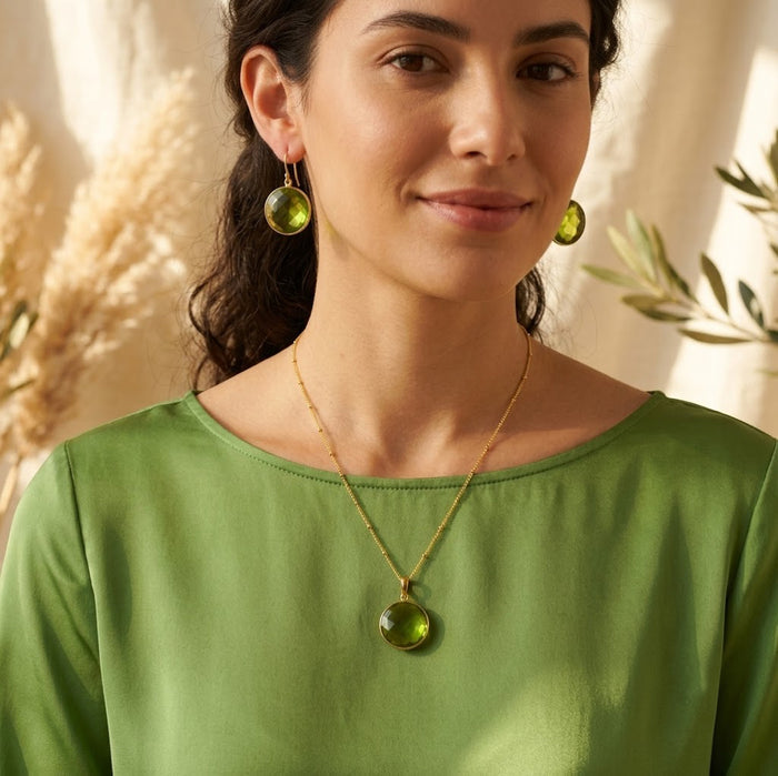 Model wearing a peridot birthstone necklace with a soft green top in natural sunlight.