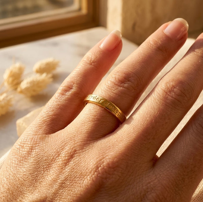 Custom engraved ring with romantic text, names, dates, coordinates, or personal message shown on hand in a close up view.