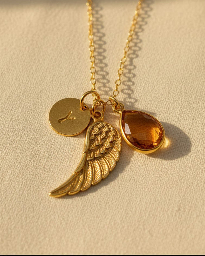 Personalized angel wing necklace featuring a natural birthstone teardrop, engraved initial disk, and gold vermeil wing charm, a meaningful memorial jewelry piece and sympathy gift for women.