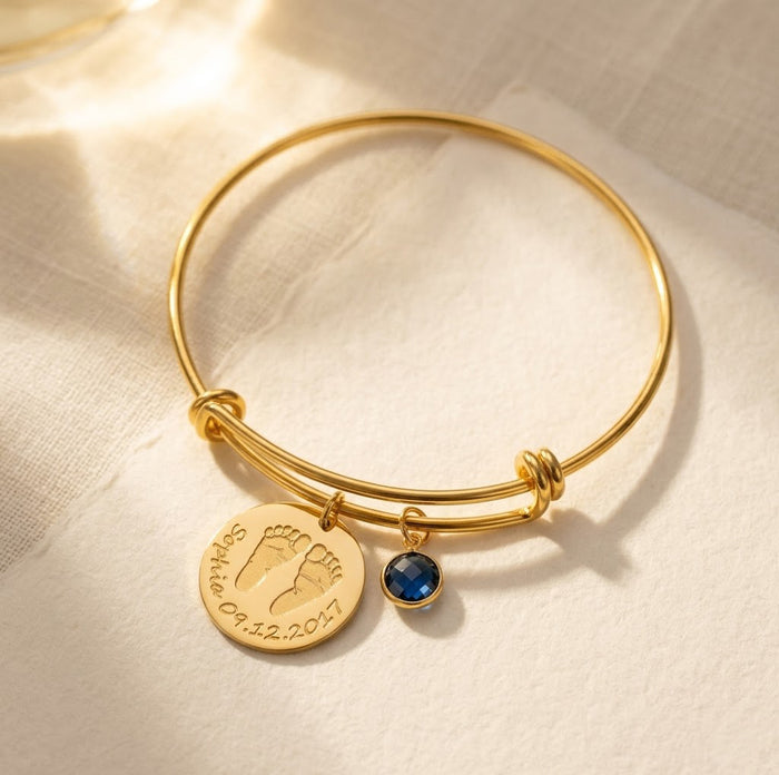 Personalized baby footprint birthstone bangle bracelet with engraved name and date, a meaningful new mom keepsake bracelet in gold.