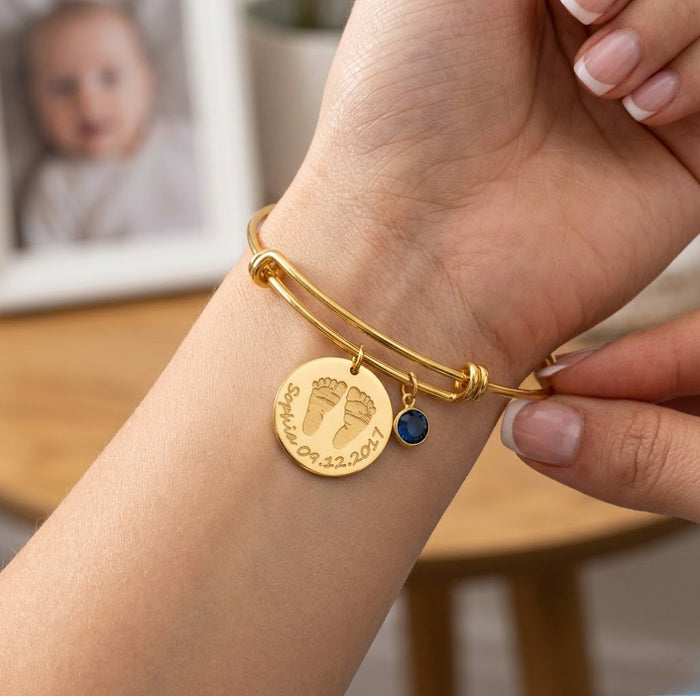 Mom wearing personalized baby footprint bangle bracelet with birthstone charm, a custom push present and new baby jewelry gift.